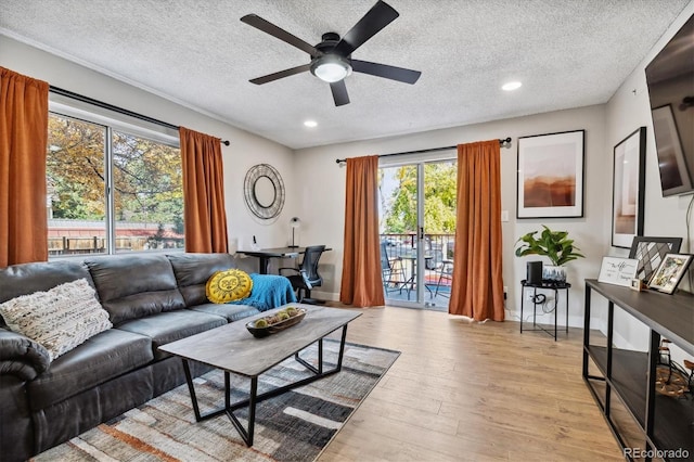 living room featuring recessed lighting, light wood-style flooring, ceiling fan, a textured ceiling, and baseboards