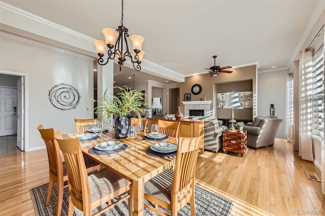 16626 Las Brisas Dr, Broomfield, CO 80023 - dining room featuring ceiling fan, light wood-type flooring, a tiled fireplace, crown molding, and a chandelier