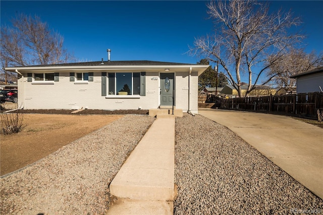 ranch-style house featuring fence and brick siding