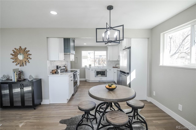 kitchen featuring baseboards, light countertops, appliances with stainless steel finishes, light wood-type flooring, and backsplash