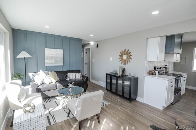 living area with light wood-type flooring, baseboards, and recessed lighting