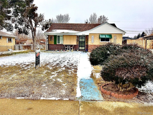 ranch-style home featuring brick siding and fence