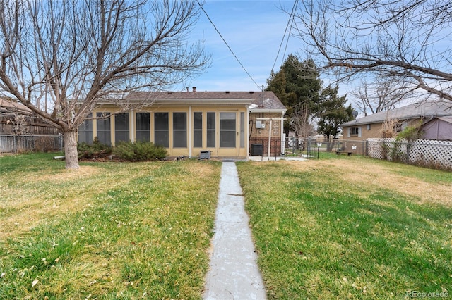 back of house featuring a yard, brick siding, a fenced backyard, and a sunroom