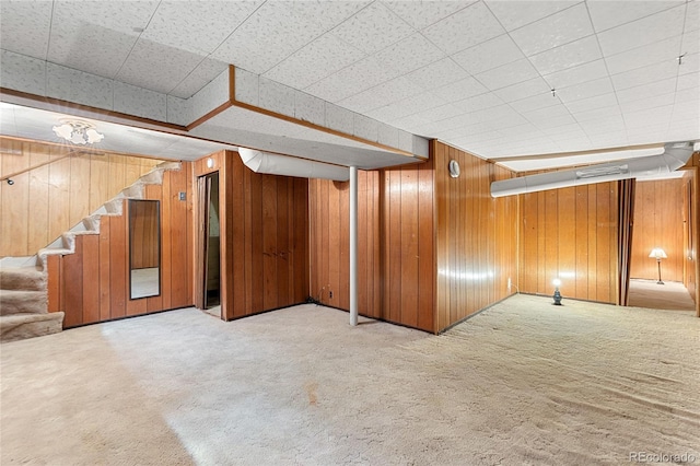 finished below grade area featuring wood walls, stairway, and light carpet