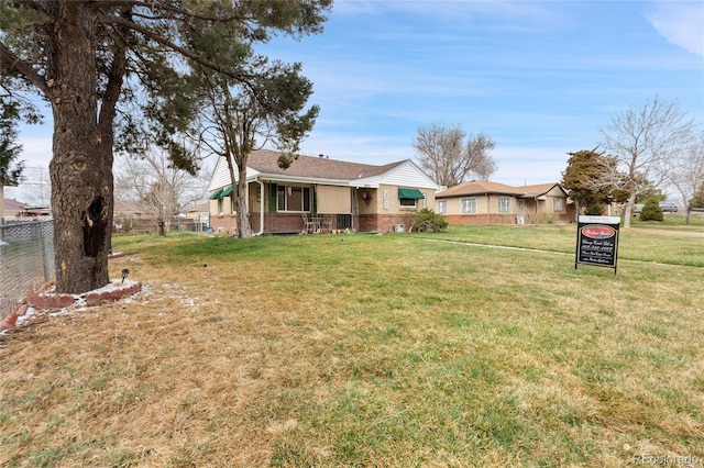 view of front of home featuring fence, a front lawn, and brick siding