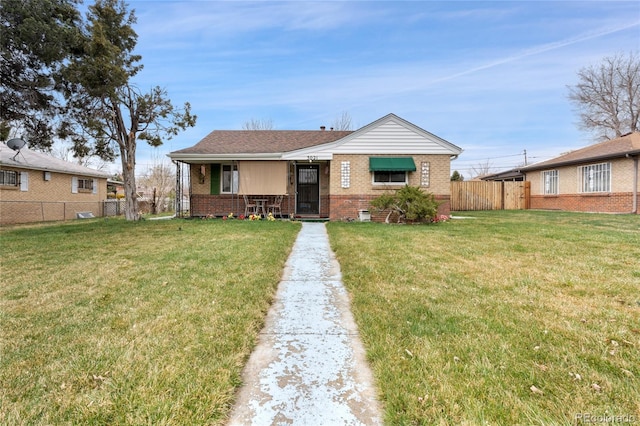 view of front facade with a front yard, fence, and brick siding