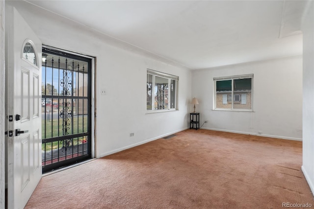 empty room with carpet flooring, visible vents, and plenty of natural light