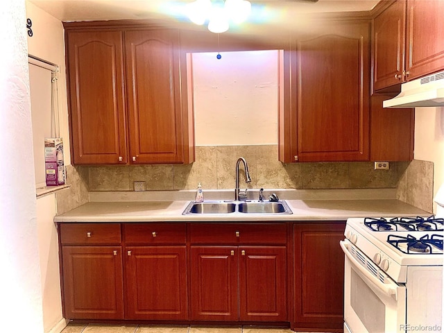 kitchen with light countertops, tasteful backsplash, white range with gas cooktop, and a sink