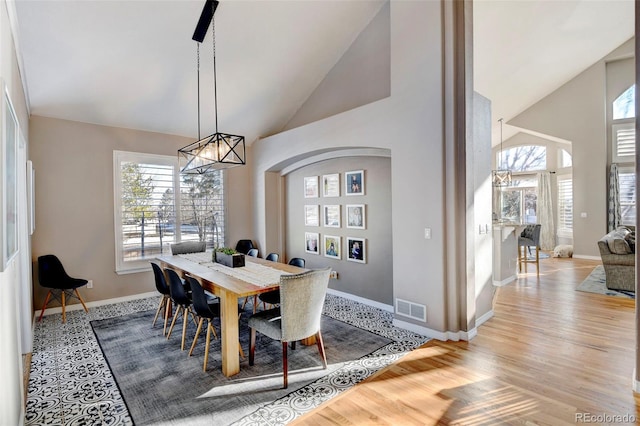 dining space featuring high vaulted ceiling and light hardwood / wood-style flooring