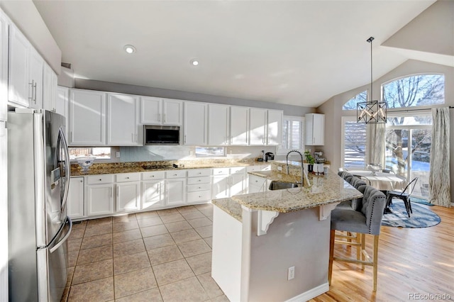 kitchen featuring sink, vaulted ceiling, decorative light fixtures, white cabinets, and appliances with stainless steel finishes