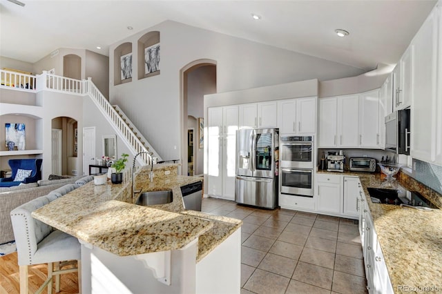 kitchen with a breakfast bar area, sink, a center island with sink, and appliances with stainless steel finishes