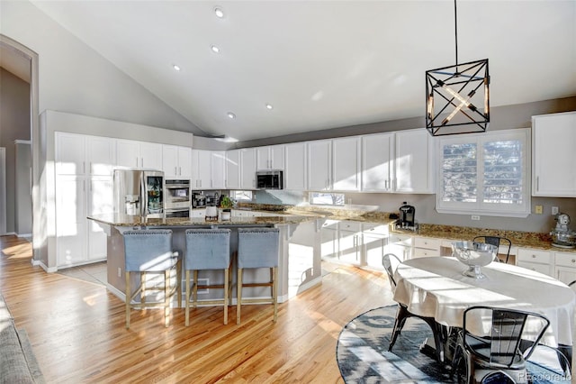 kitchen with white cabinetry, a kitchen island, stone countertops, and appliances with stainless steel finishes