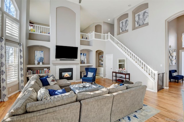 living room featuring a towering ceiling, built in features, and a wealth of natural light