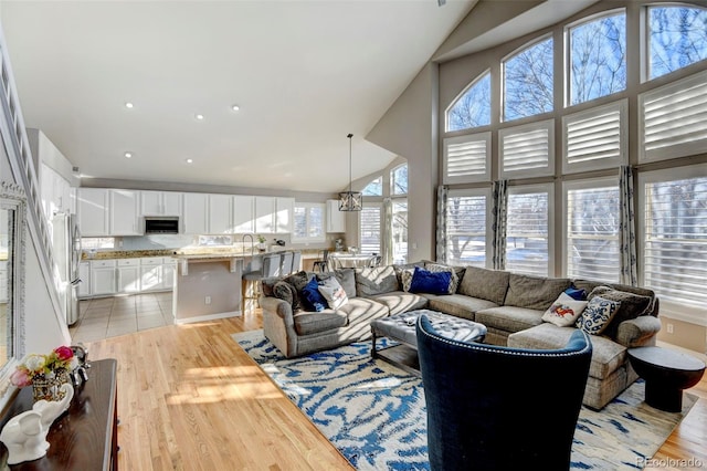 living room featuring sink, high vaulted ceiling, and light hardwood / wood-style flooring