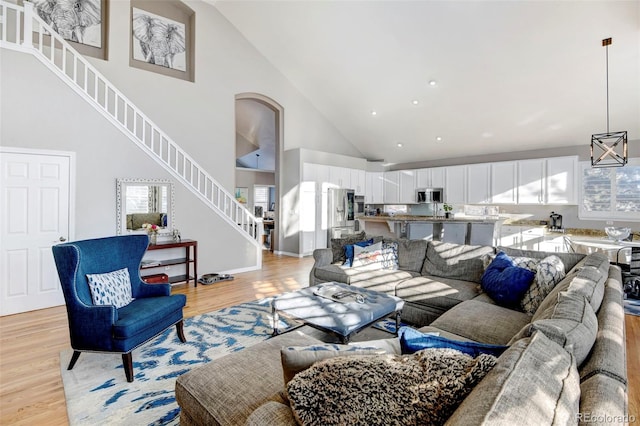 living room with light wood-type flooring and high vaulted ceiling