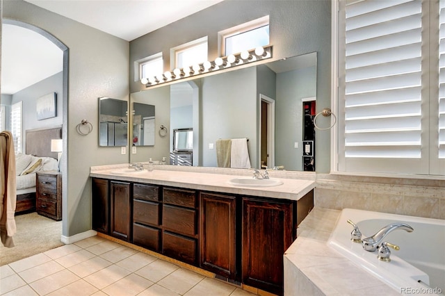 bathroom featuring tile patterned floors, a relaxing tiled tub, and vanity