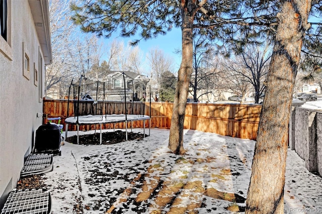 yard layered in snow featuring a trampoline