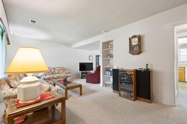 living room featuring a textured ceiling, carpet, and built in shelves