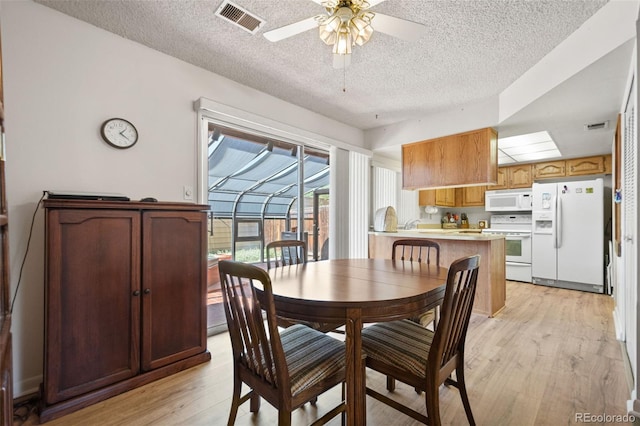 dining area with ceiling fan, a textured ceiling, and light wood-type flooring