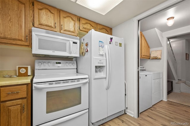 kitchen featuring independent washer and dryer, light hardwood / wood-style floors, and white appliances