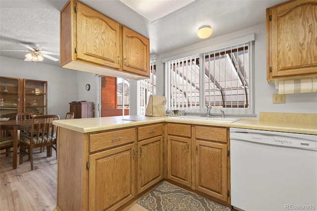 kitchen featuring light hardwood / wood-style floors, kitchen peninsula, dishwasher, ceiling fan, and sink