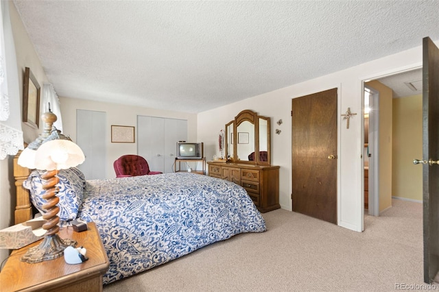 bedroom with light colored carpet and a textured ceiling