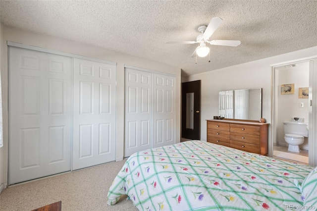 bedroom featuring a textured ceiling, carpet flooring, connected bathroom, two closets, and ceiling fan