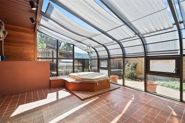 unfurnished sunroom featuring lofted ceiling and a jacuzzi