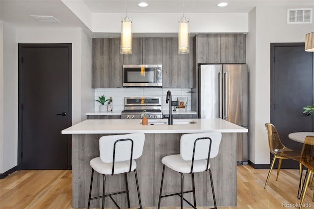 kitchen featuring stainless steel appliances, modern cabinets, light countertops, and visible vents