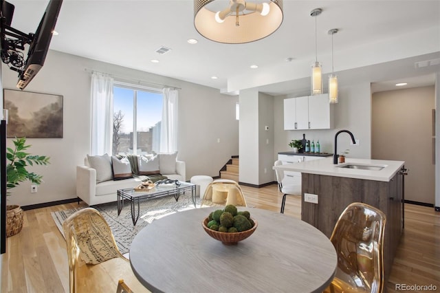 dining room with light wood finished floors, baseboards, visible vents, and recessed lighting