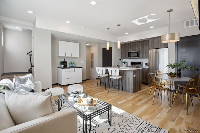 living room with recessed lighting, visible vents, and light wood-style floors