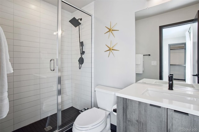 bathroom with a shower stall, toilet, and vanity