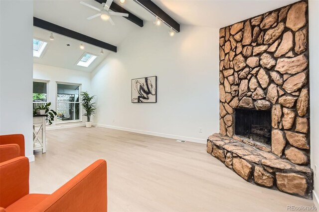 10295 E Evans Ave Unit 114, Aurora, CO 80247 - living area featuring beamed ceiling, a skylight, a stone fireplace, a ceiling fan, and high vaulted ceiling
