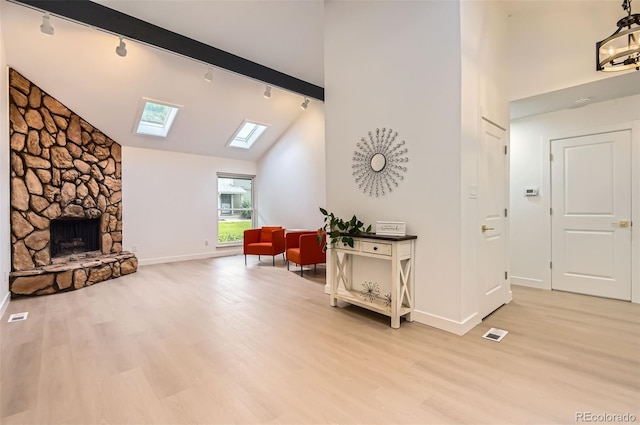 10295 E Evans Ave Unit 114, Aurora, CO 80247 - sitting room featuring track lighting, a skylight, high vaulted ceiling, light wood-type flooring, and a stone fireplace
