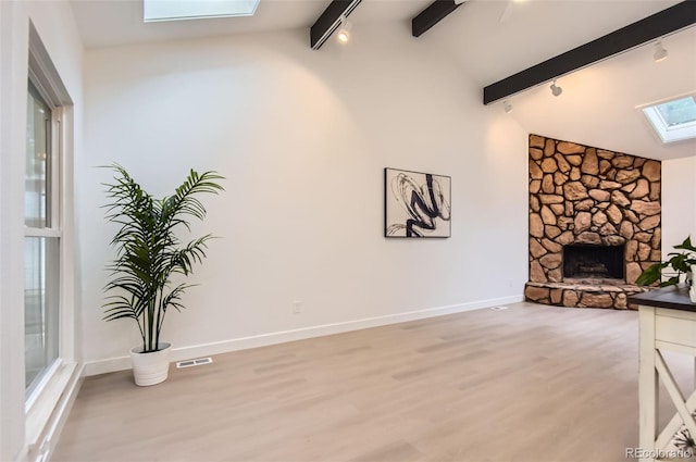 10295 E Evans Ave Unit 114, Aurora, CO 80247 - unfurnished living room with rail lighting, a skylight, a fireplace, beamed ceiling, and light wood finished floors
