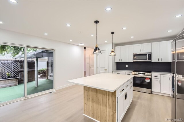 10295 E Evans Ave Unit 114, Aurora, CO 80247 - kitchen featuring stainless steel appliances, light wood finished floors, white cabinetry, decorative backsplash, and a kitchen island