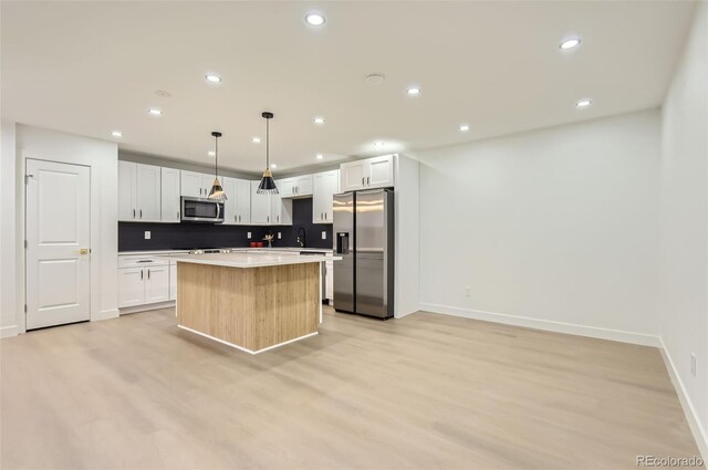 10295 E Evans Ave Unit 114, Aurora, CO 80247 - kitchen with appliances with stainless steel finishes, a center island, decorative backsplash, recessed lighting, and light wood-style floors