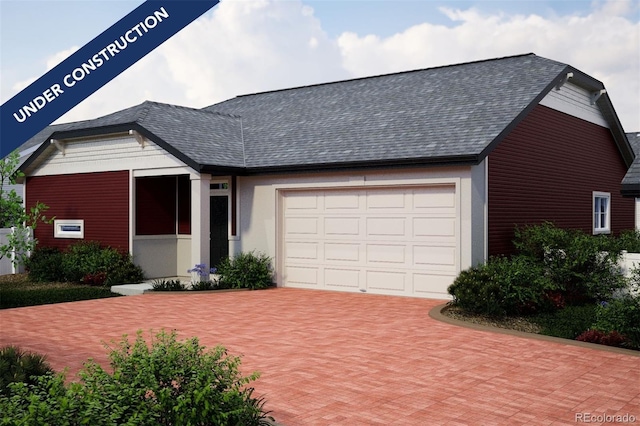 ranch-style house featuring roof with shingles, an attached garage, and decorative driveway