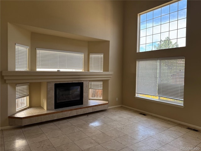 20304 E 47th Pl, Denver, CO 80249 - unfurnished living room featuring baseboards, a fireplace, tile patterned flooring, and a high ceiling