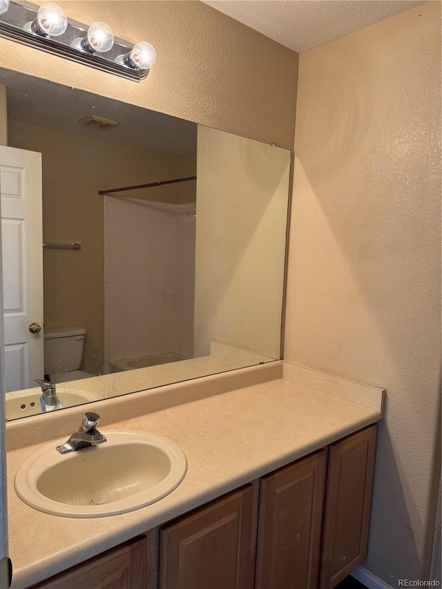 20304 E 47th Pl, Denver, CO 80249 - bathroom featuring toilet, vanity, a shower, and a textured ceiling