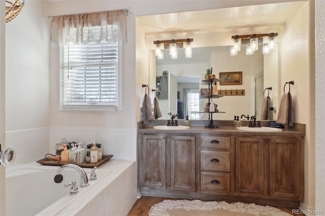 bathroom featuring a relaxing tiled tub, a wealth of natural light, and vanity