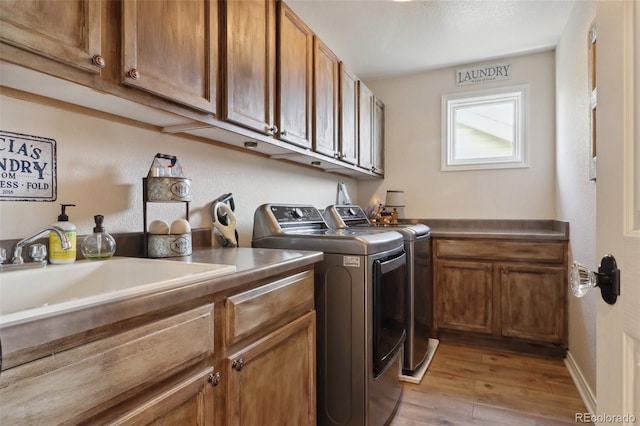 laundry room featuring cabinets, light hardwood / wood-style flooring, sink, and independent washer and dryer