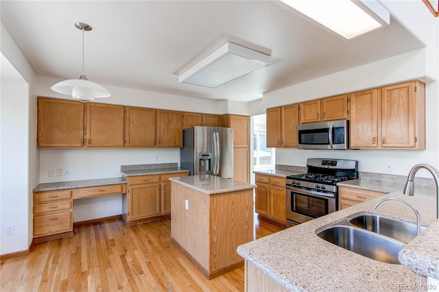 kitchen featuring appliances with stainless steel finishes, a sink, a center island, hanging light fixtures, and light wood finished floors