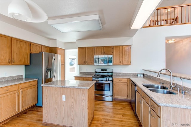 kitchen featuring stainless steel appliances, a sink, a peninsula, light wood-style floors, and light stone countertops
