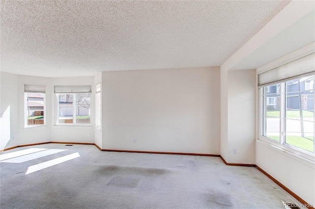unfurnished room with carpet floors, a textured ceiling, and baseboards