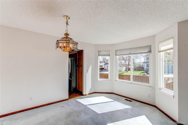 empty room featuring carpet flooring, baseboards, a chandelier, and a textured ceiling