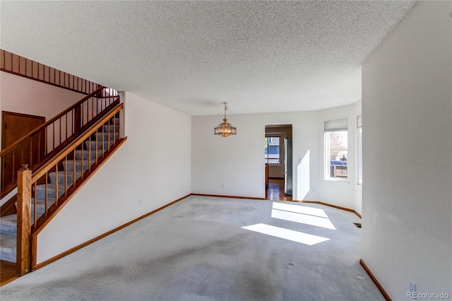 unfurnished living room with baseboards, carpet flooring, stairs, a chandelier, and a textured ceiling