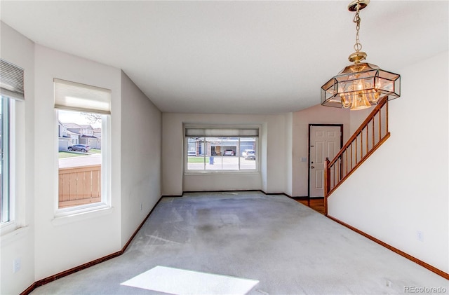 carpeted foyer entrance with plenty of natural light, a chandelier, and baseboards