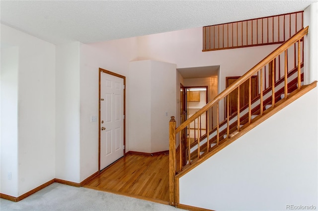 entryway featuring baseboards, stairway, carpet floors, and a textured ceiling