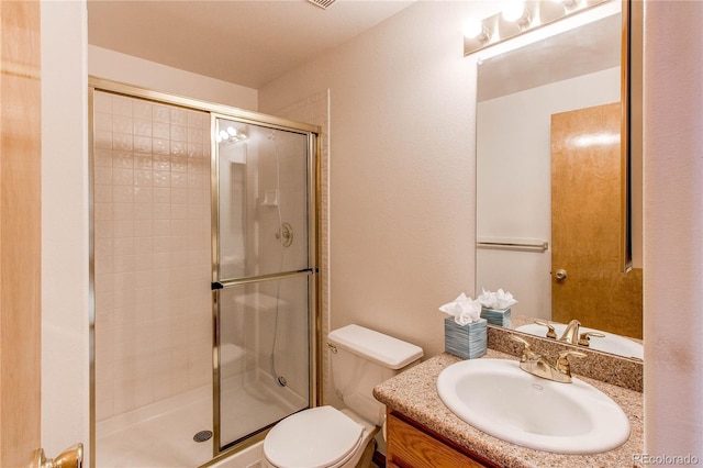 bathroom with a shower stall, toilet, and vanity